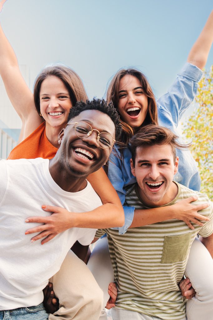 vertical-portrait-of-two-multiracial-young-friends-giving-piggyback-ride-to-his-girlfriends-a-group.jpg