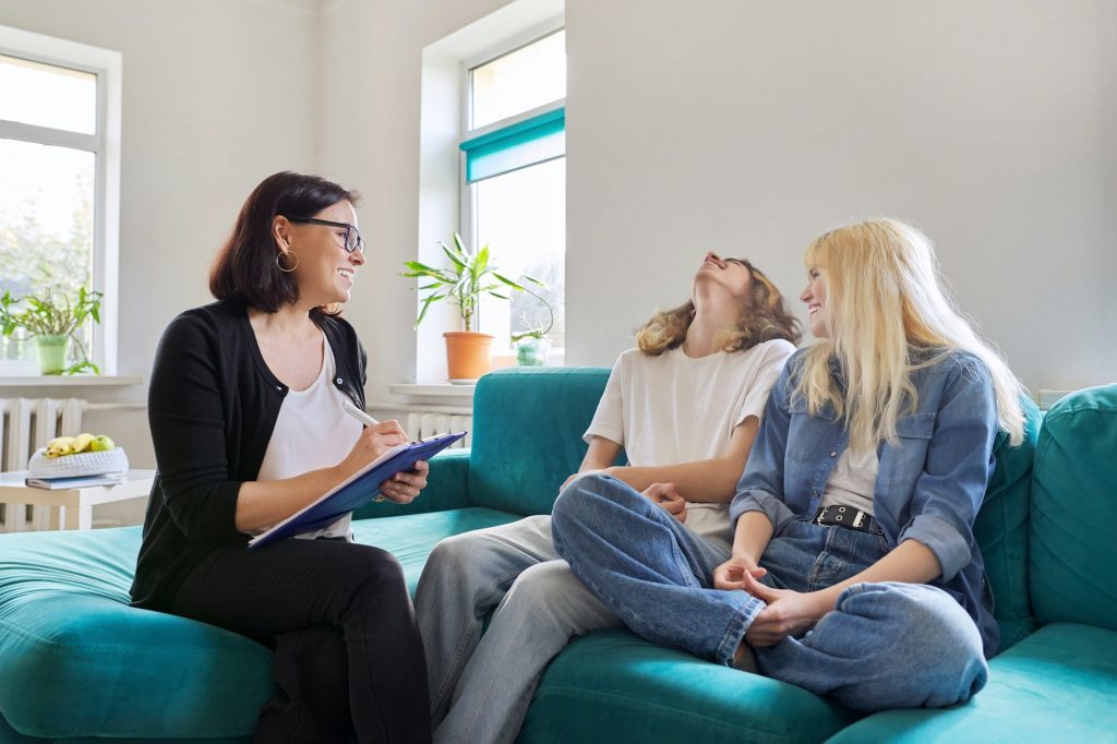 Professional female social worker, teacher, counselor, psychologist talking with teenagers